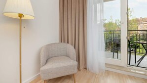 A modern living room with a sofa, a floor lamp, and a view of a balcony with outdoor furniture. - Spacious Apartment with Balcony | 2 Bedrooms | Gdansk Wrzeszcz (Gdańsk)