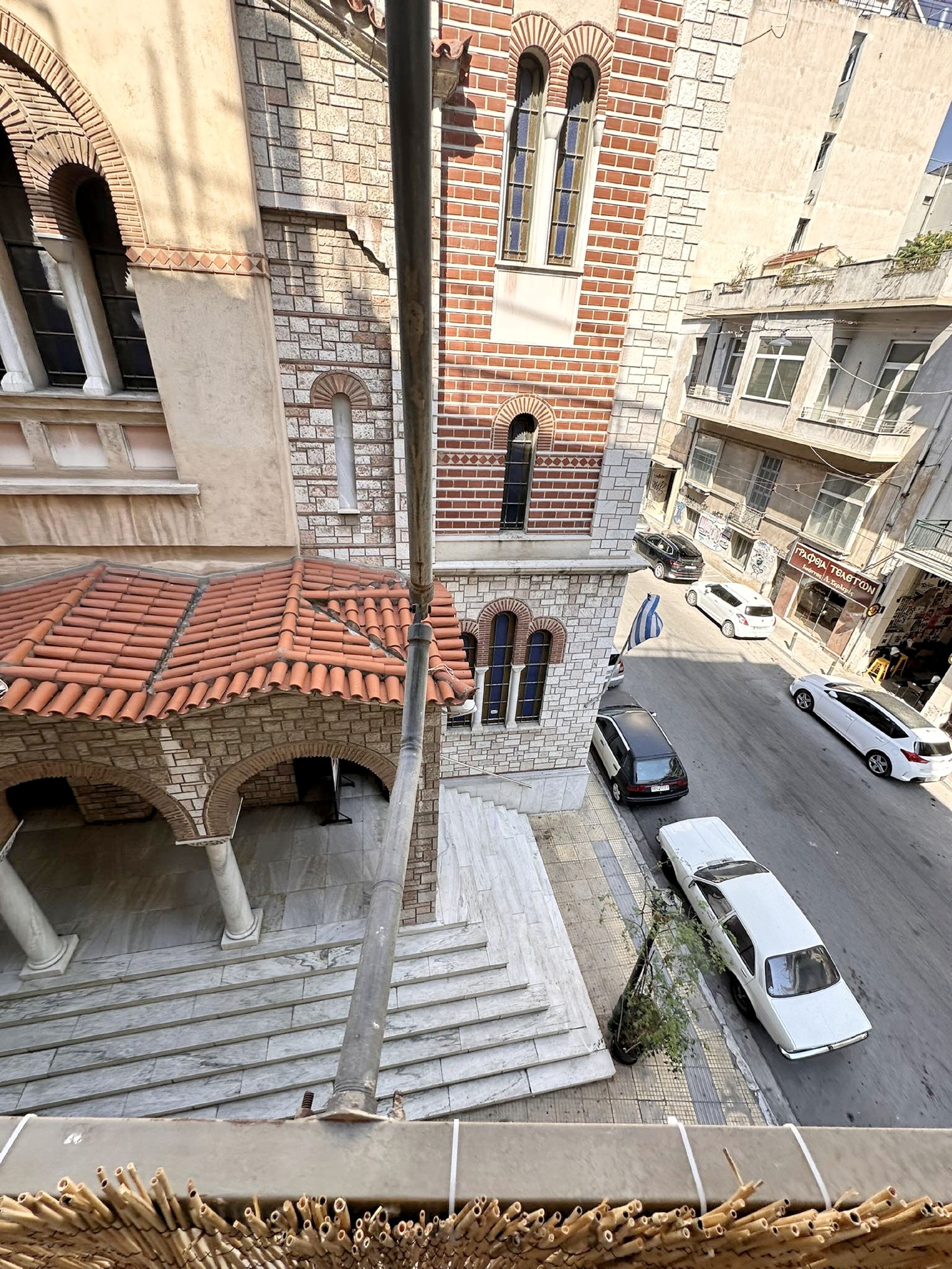 Vista de calle con un edificio de techo a dos aguas, paredes de ladrillo y ventanas de arco.
