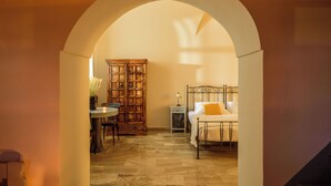 A hallway with a bed, a cabinet, and a table with candles. - Ikio Concept Santorini (Santorini)