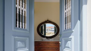 A hallway with a blue door, a wooden dresser, and a mirror on the wall. - Ikio Concept Santorini (Santorini)