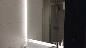 A modern bathroom with a large mirror, a black sink, and a shower area. - Theodosius Hotel (Istanbul)
