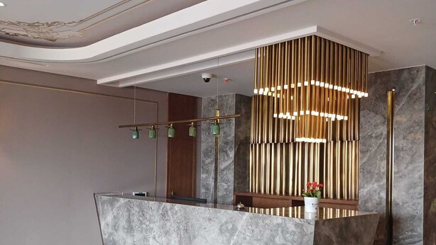 A reception desk with a marble top, a modern pendant light, and a security camera above. - Theodosius Hotel (Istanbul)