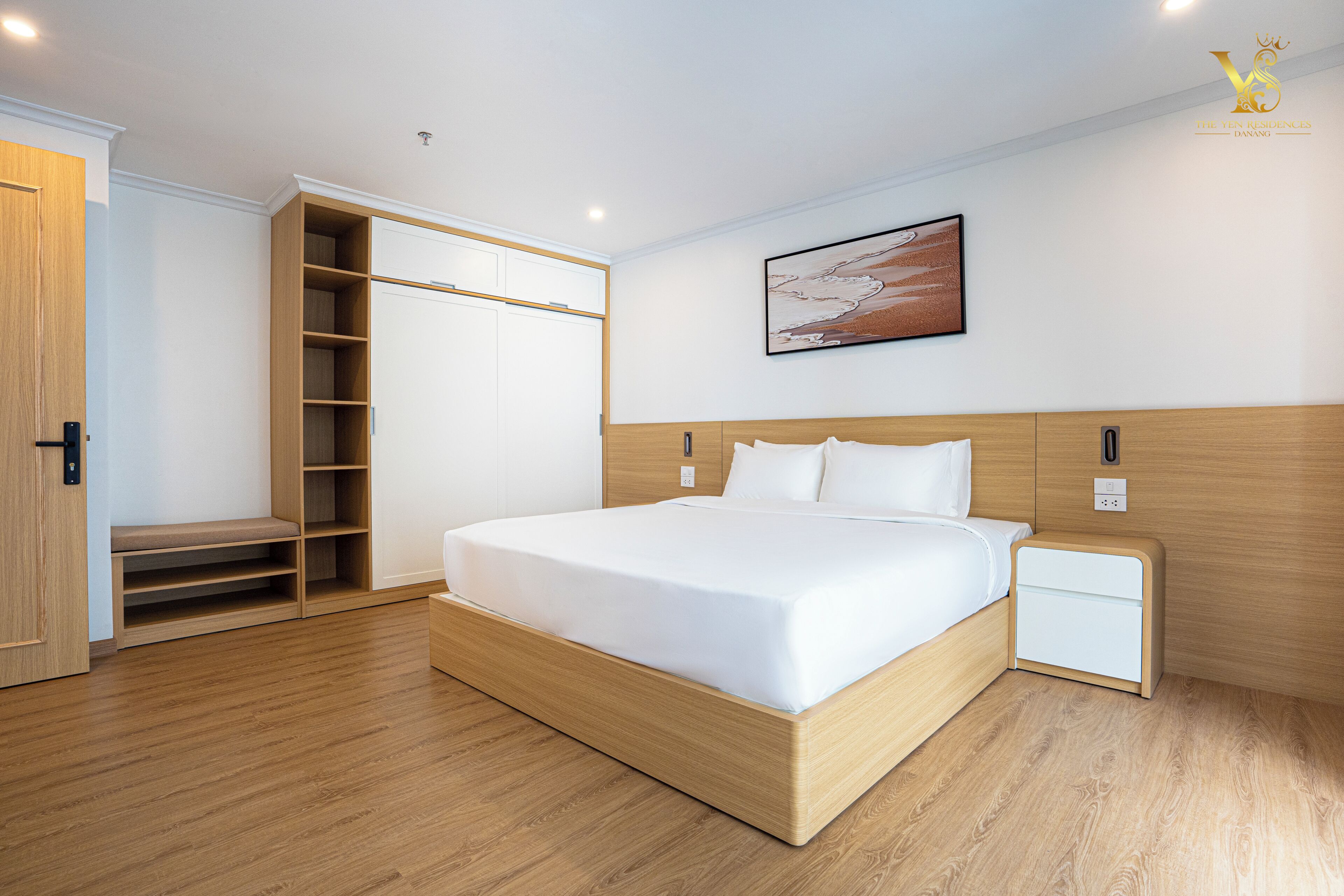 Ein modernes Schlafzimmer mit einem hölzernen Bett, einem Nachttisch, einem Einbauschrank und Strandkunst an der Wand.