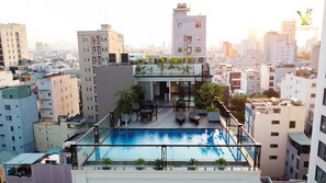 A rooftop pool with a glass barrier, surrounded by potted plants and outdoor seating. - The Yen Residences Danang (Da Nang)