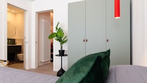 Un dormitorio con cama, armario, radiador y planta en maceta.