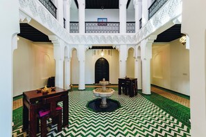 Enjoy the serene ambiance of this stylish space, featuring a central fountain, elegant tables, and a high ceiling with intricate details.