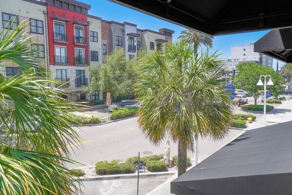 A view of a multi-story building with balconies, a parking lot, and palm trees.