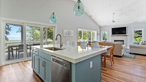 A modern kitchen with a large island, wooden flooring, and a view of the outdoors. - Assateague Holiday House Nature & Luxury Combined (Berlin)