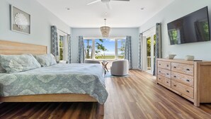 A bedroom with a bed, a ceiling fan, a chandelier, a TV, and a view of the outdoors. - Assateague Holiday House Nature & Luxury Combined (Berlin)