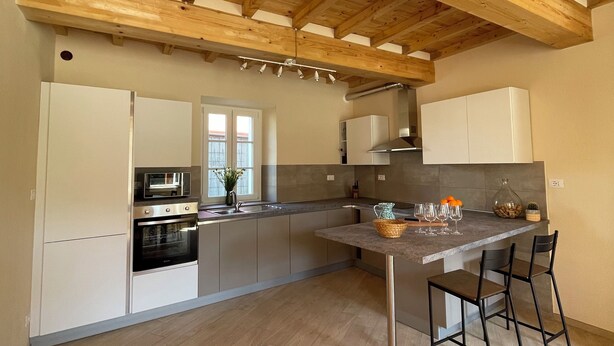A modern kitchen with wooden beams, stainless steel appliances, and a central island with bar stools.