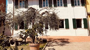 A courtyard with a building featuring a tiled roof, multiple windows with shutters, and a satellite dish.
