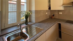 A modern kitchen with a large island, stainless steel sink, and wooden ceiling beams.