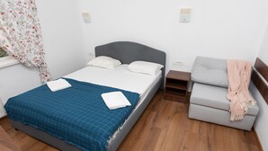 Un dormitorio con cama, sofá y suelo de madera.