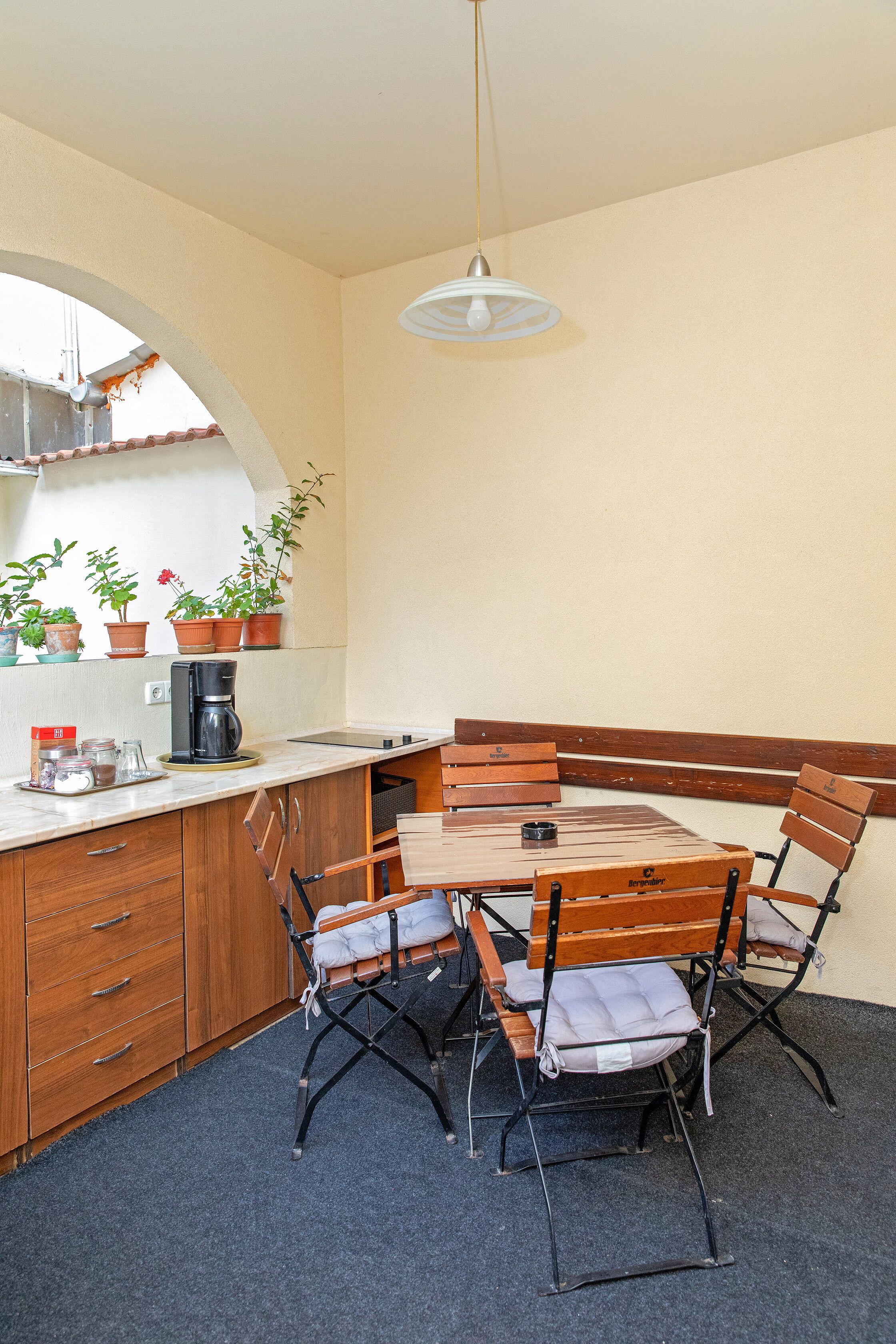A compact kitchen with wooden cabinets, a built-in bench, and a coffee maker.