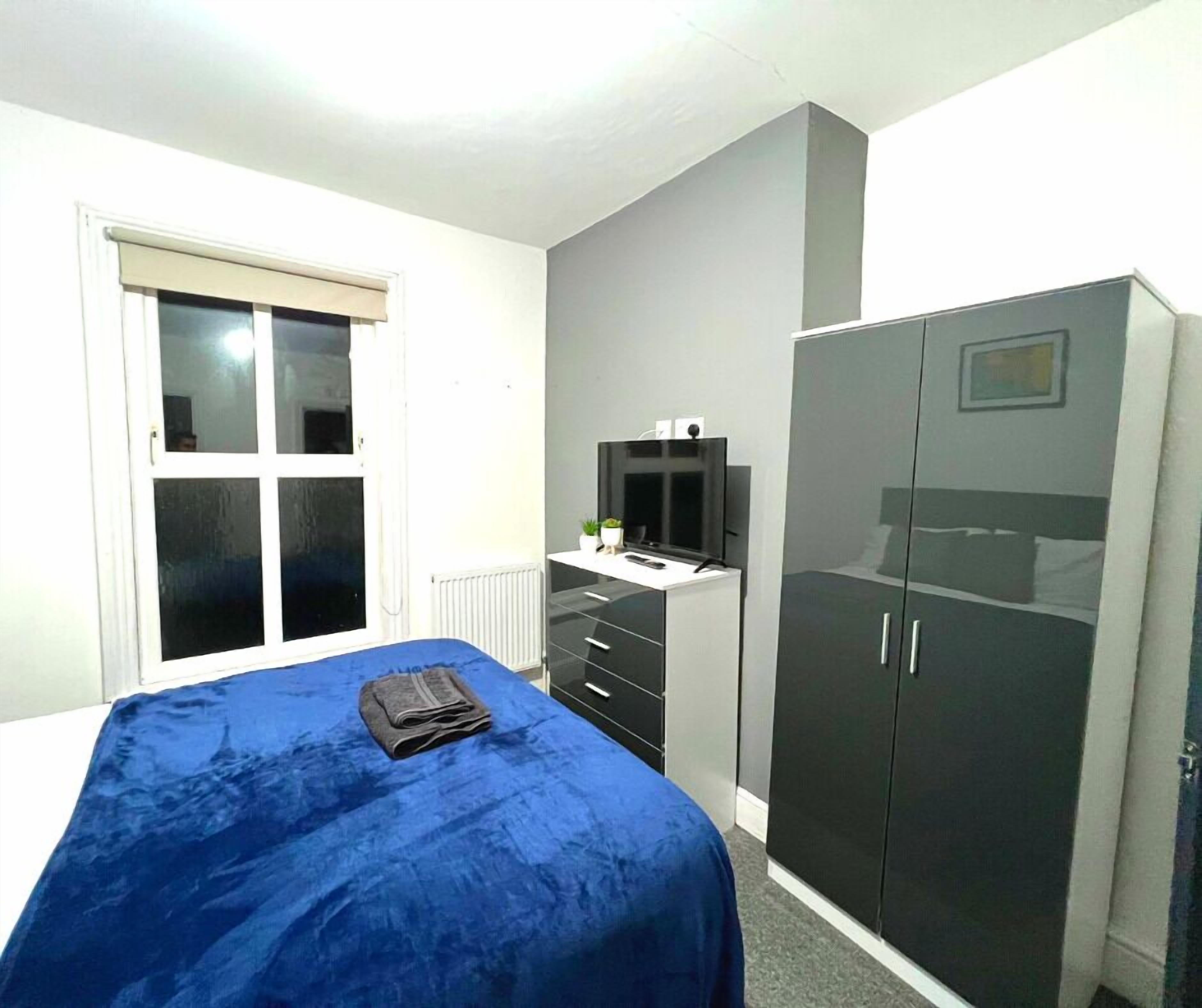 Un dormitorio con una cama, un armario, un televisor y una ventana.