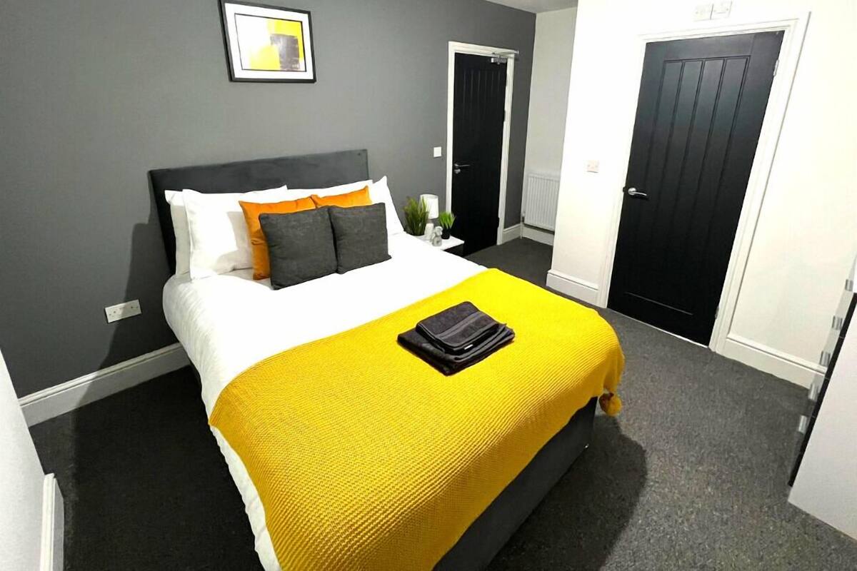 Une chambre d’hôtel moderne avec un grand lit, une table de chevet et une commode, ainsi qu’une porte.