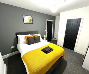 Ein modernes Hotelzimmer mit einem großen Bett, einem Nachttisch und einer Tür.