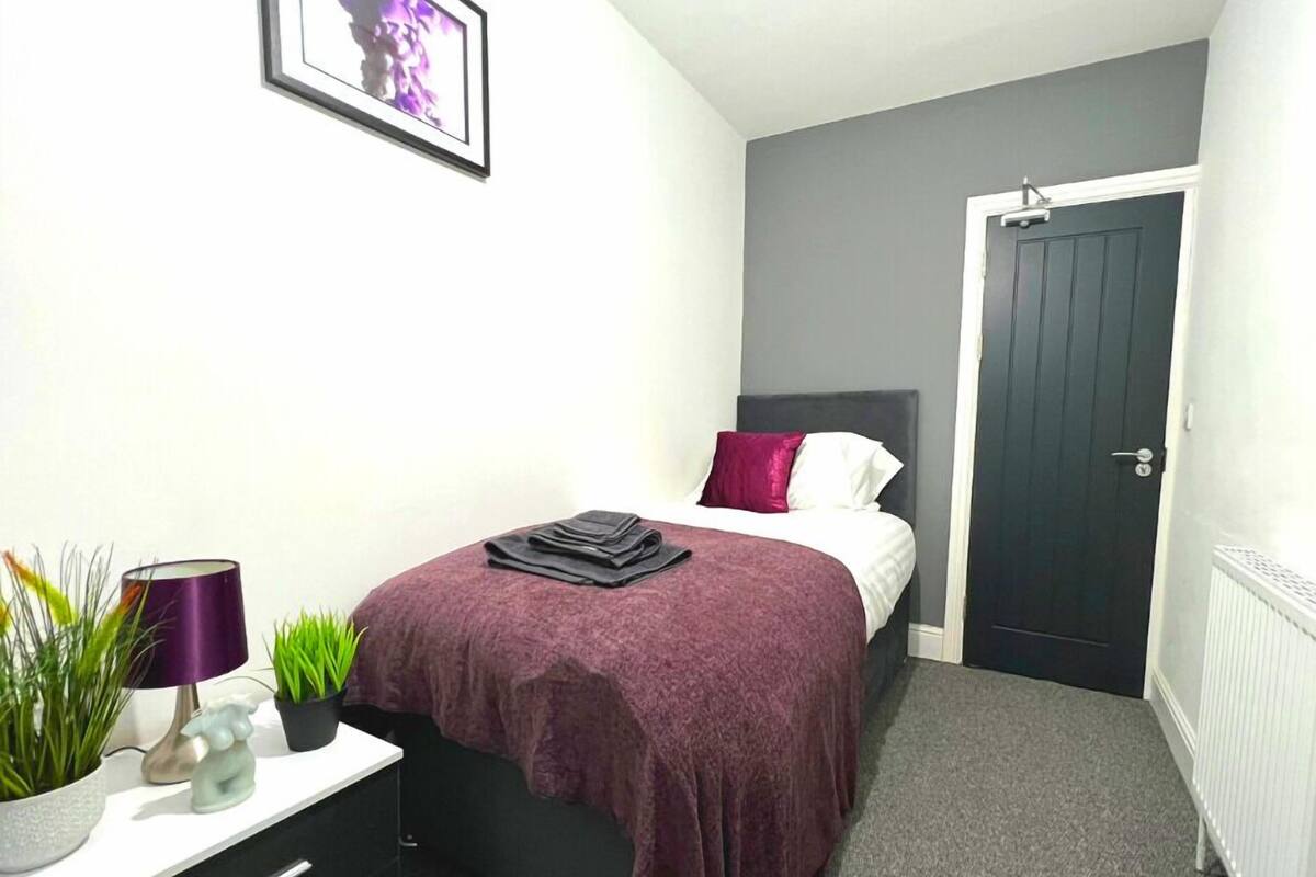 Une chambre à coucher avec un lit, une table de chevet, une lampe et une plante en pot.