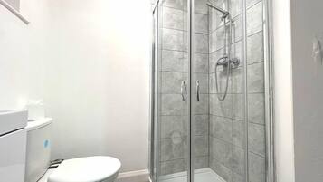 A modern bathroom with a glass-enclosed shower, a toilet, and a sink.