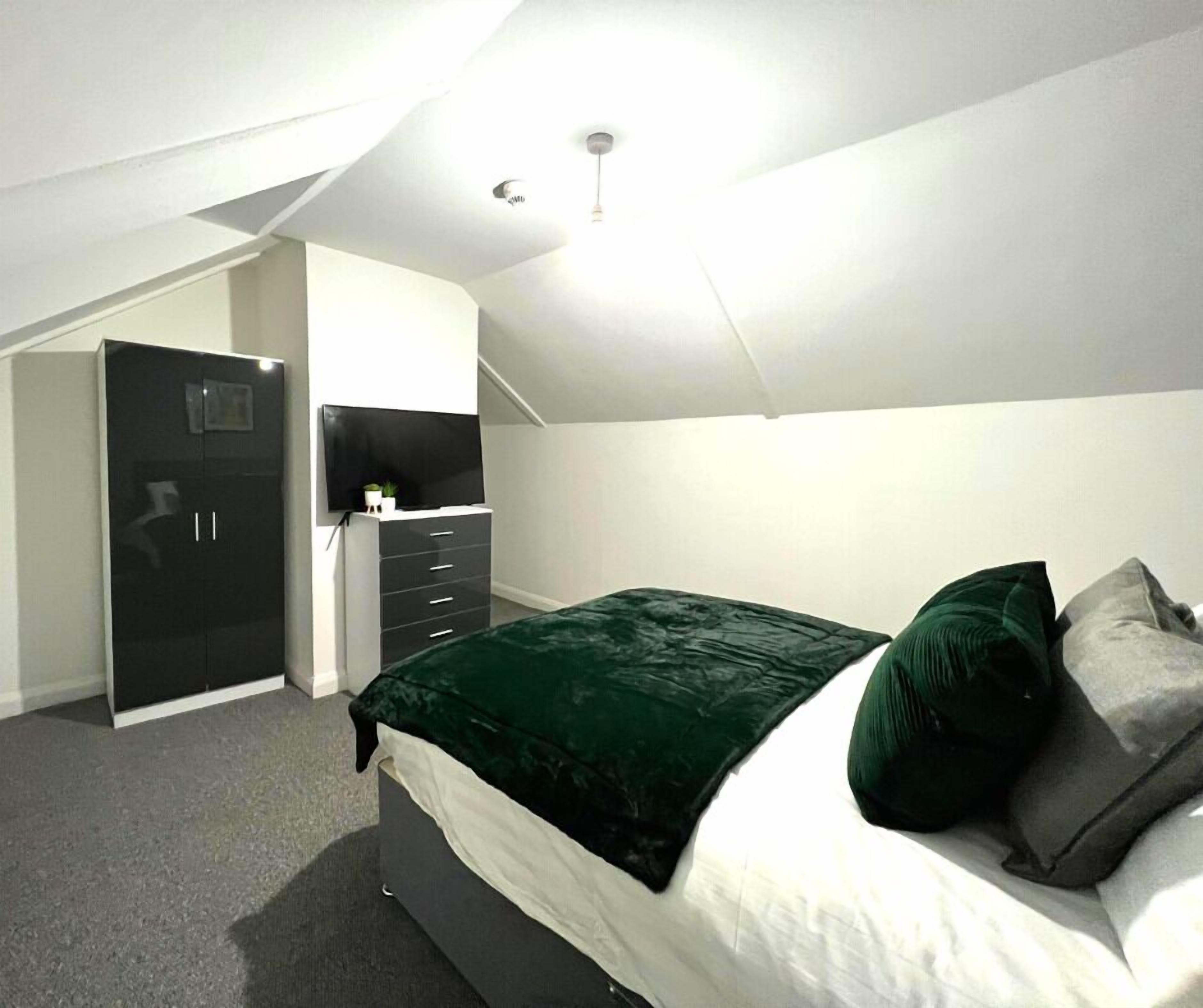 Un dormitorio con cama, armario, escritorio y televisor.
