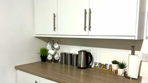 A kitchen with white cabinets, a wooden countertop, stainless steel appliances, and decorative items. - Chantry Suites by SA Stays (Grimsby)