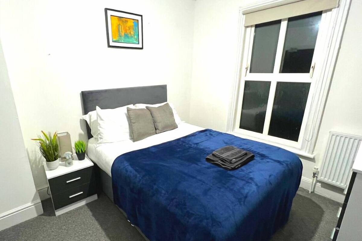 Une chambre à coucher bien rangée, avec un lit, une table de chevet et une fenêtre.