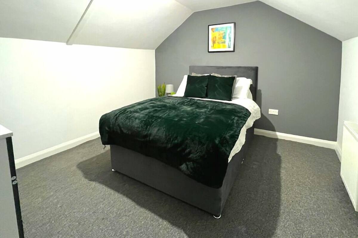 Une chambre à coucher avec un lit, une table de chevet, une lampe et un tableau encadré au mur.