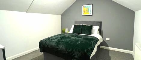 A bedroom with a bed, a nightstand, a lamp, and a framed picture on the wall.