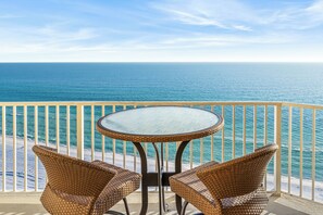 Ein Balkon mit Korbstühlen und einem Glastisch mit Blick auf den Ozean.
