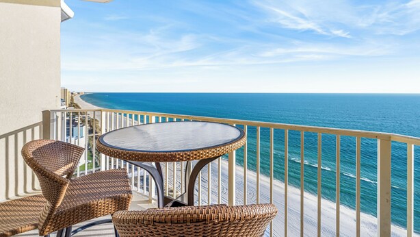 A balcony with wicker furniture and a view of the ocean.