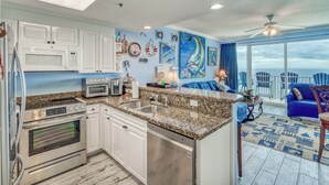 A kitchen with granite countertops, white cabinets, a built-in oven, and a dishwasher. - Popular Escape in a Private Paradise (Panama City Beach)