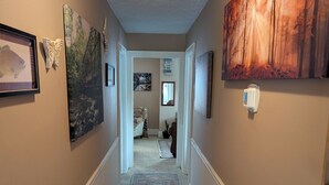 A hallway with a patterned carpet, framed artwork, and a thermostat on the wall. - Cozy home in Damascus located next to River, Trails, Bike Shops, and Dining. (Damascus)