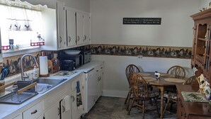 A kitchen with white cabinets, a dining table with chairs, a window with curtains, and a decorative wall sign. - Cozy home in Damascus located next to River, Trails, Bike Shops, and Dining. (Damascus)