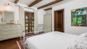 A bedroom with a bed, dresser, and a painting on the wall.