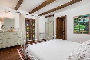 A bedroom with a bed, dresser, and a painting on the wall.