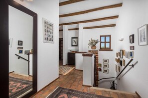 A hallway with a wooden staircase, a mirror, and a wall adorned with framed pictures.