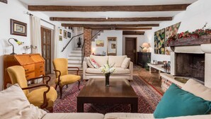 A cozy living room with a sofa, armchairs, a wooden coffee table, and a fireplace.