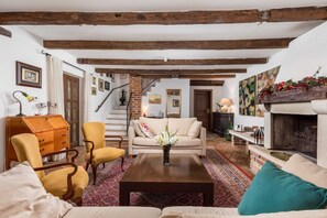 A cozy living room with a sofa, armchairs, a wooden coffee table, and a fireplace.