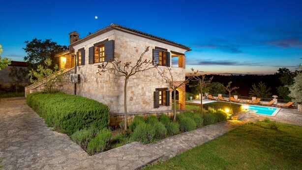A stone house with a swimming pool, outdoor seating, and a well-maintained garden.