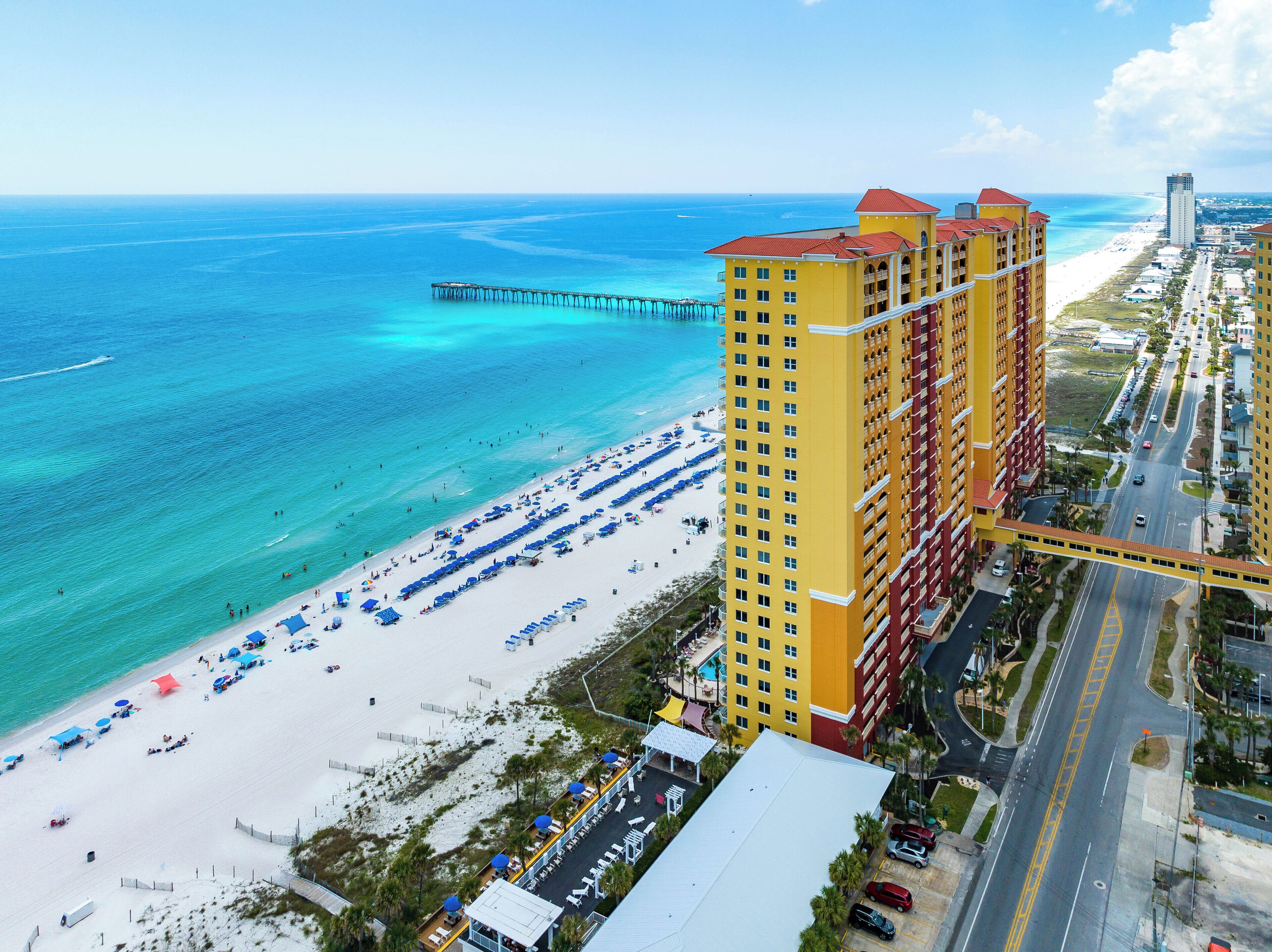 Ein Hochhaus-Hotel mit Blick auf den Strand, einer Pier und einer Straße mit parkenden Autos.