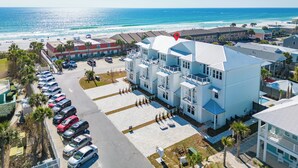 A coastal hotel with multiple floors, a parking lot, and a view of the beach and ocean. - New Luxury Beach Home with Private Pool (Panama City Beach)