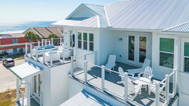 A white beachfront property with a balcony, multiple windows, and a view of the ocean. - New Luxury Beach Home with Private Pool (Panama City Beach)