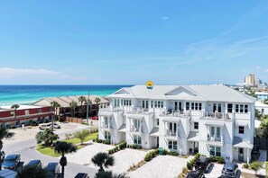A multi-story hotel with a beach view, featuring balconies and a sign indicating a location.