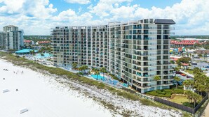 A modern hotel with multiple balconies, a pool area, and a beach view. - Tropical Beachfront Retreat (Panama City Beach)