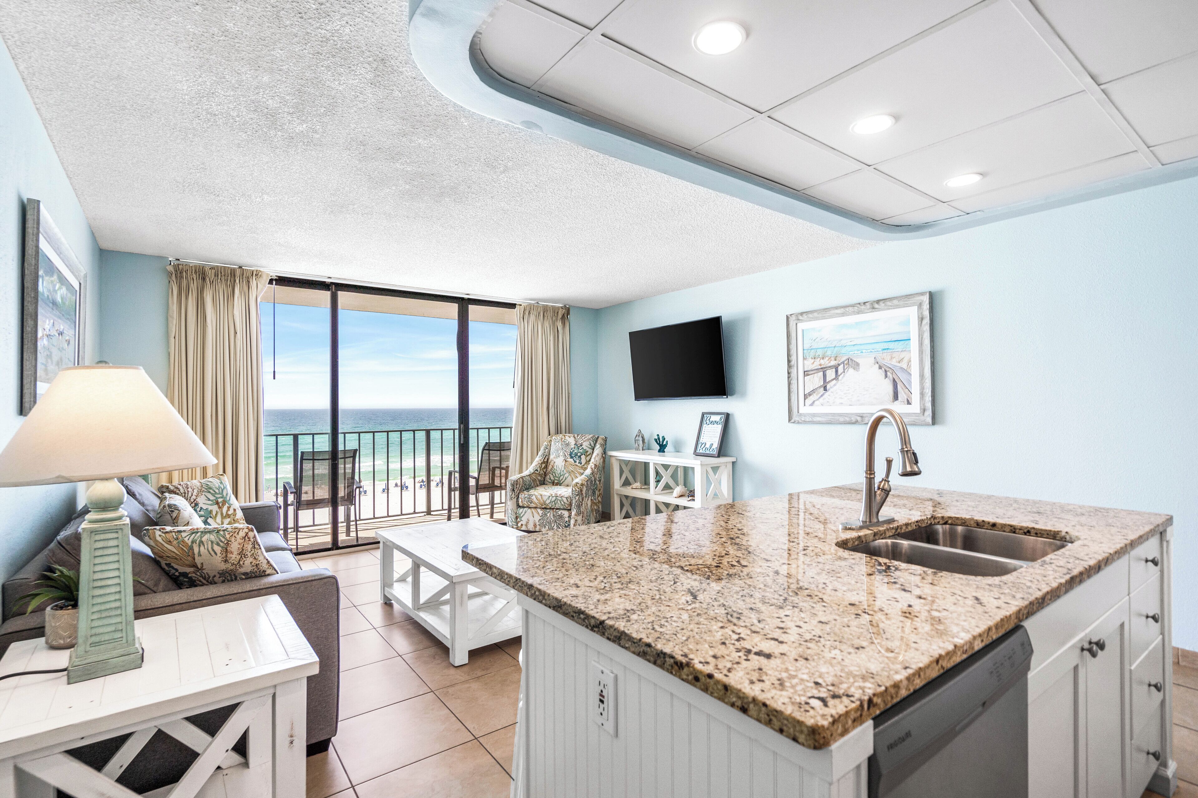 A modern kitchen with a granite countertop, white cabinetry, and a built-in dishwasher.