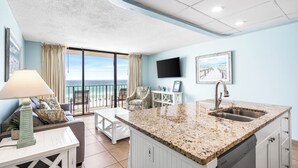 A modern kitchen with a granite countertop, white cabinetry, and a built-in dishwasher. - Tropical Beachfront Retreat (Panama City Beach)
