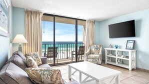 A living room with a sofa, coffee table, and a TV mounted on the wall. - Tropical Beachfront Retreat (Panama City Beach)