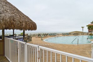 Relax by the pool overlooking the sea, surrounded by lounge chairs and a shaded area.