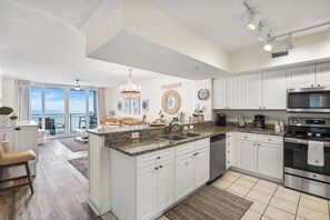 Enjoy meals in this kitchen with a large island, sink, and stainless steel appliances, offering a view of the ocean.