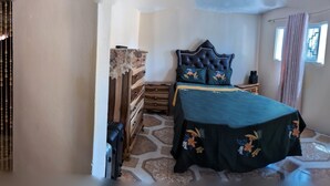 A bedroom with a bed, dresser, and a mirror. There are two suitcases in the room. - Immaculate 1-bed Apartment in Kingston 14 (Kingston)